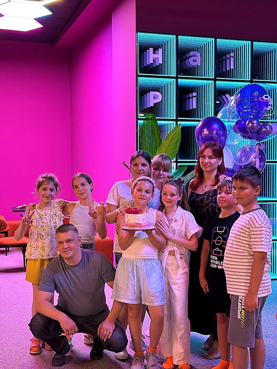 Grup de copii cu baloane la o petrecere tematică neon lângă peretele luminos Hai Pixel