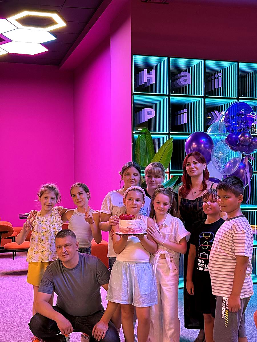 Grup de copii și părinți la masa de petrecere aniversară cu baloane și perete cu litere neon, Hai Pixel Chișinău