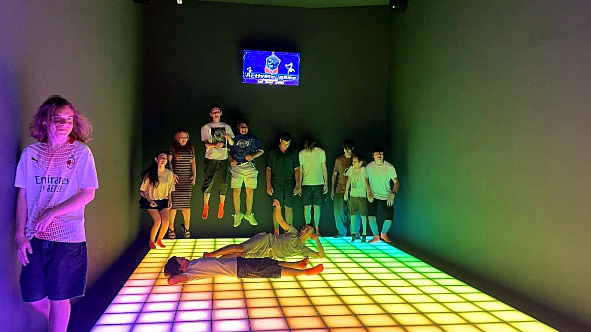 Grup de copii răspândiți pe podeaua LED colorată în timpul unui joc la Hai Pixel din Chișinău