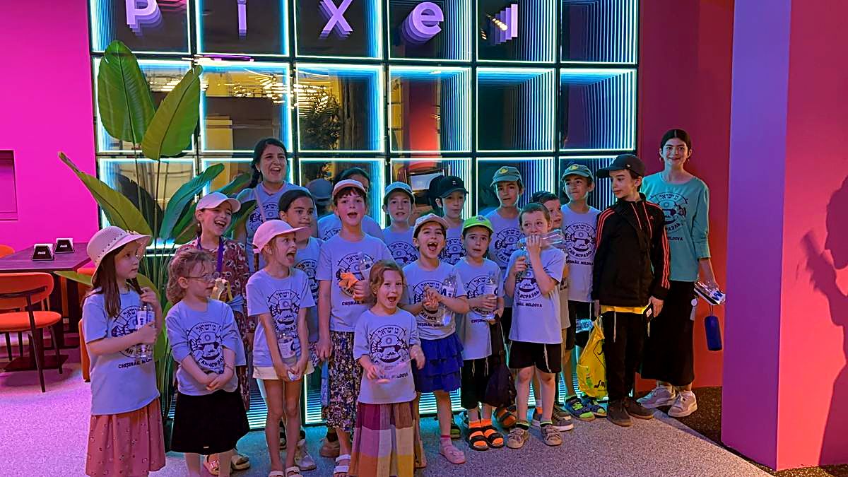 Grup mare în tricouri identice pozat în fața peretelui cu litere neon Pixel la Hai Pixel, Chișinău