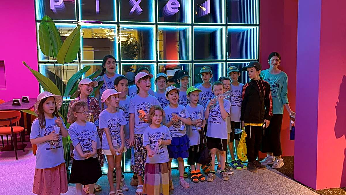 Grup fotografiat împreună la peretele cu neon Hai Pixel din Chișinău