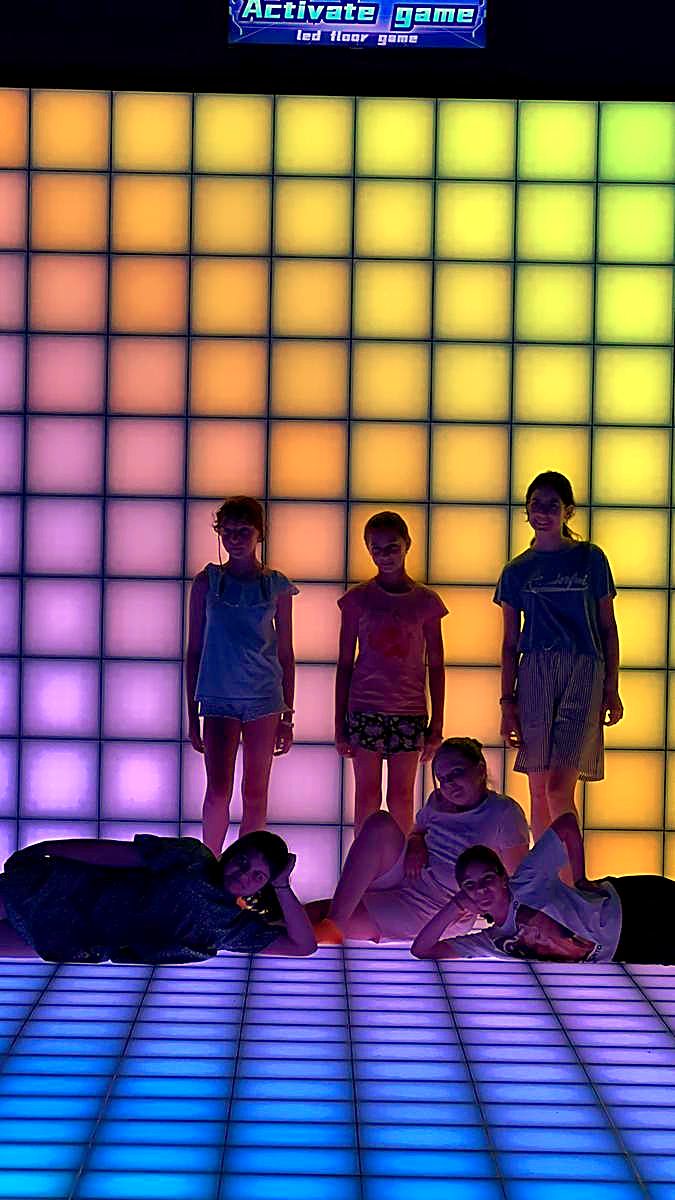 Siluete de jucători în fața peretelui LED interactiv luminat în pătrate albastru pastel și verde la Hai Pixel Chișinău