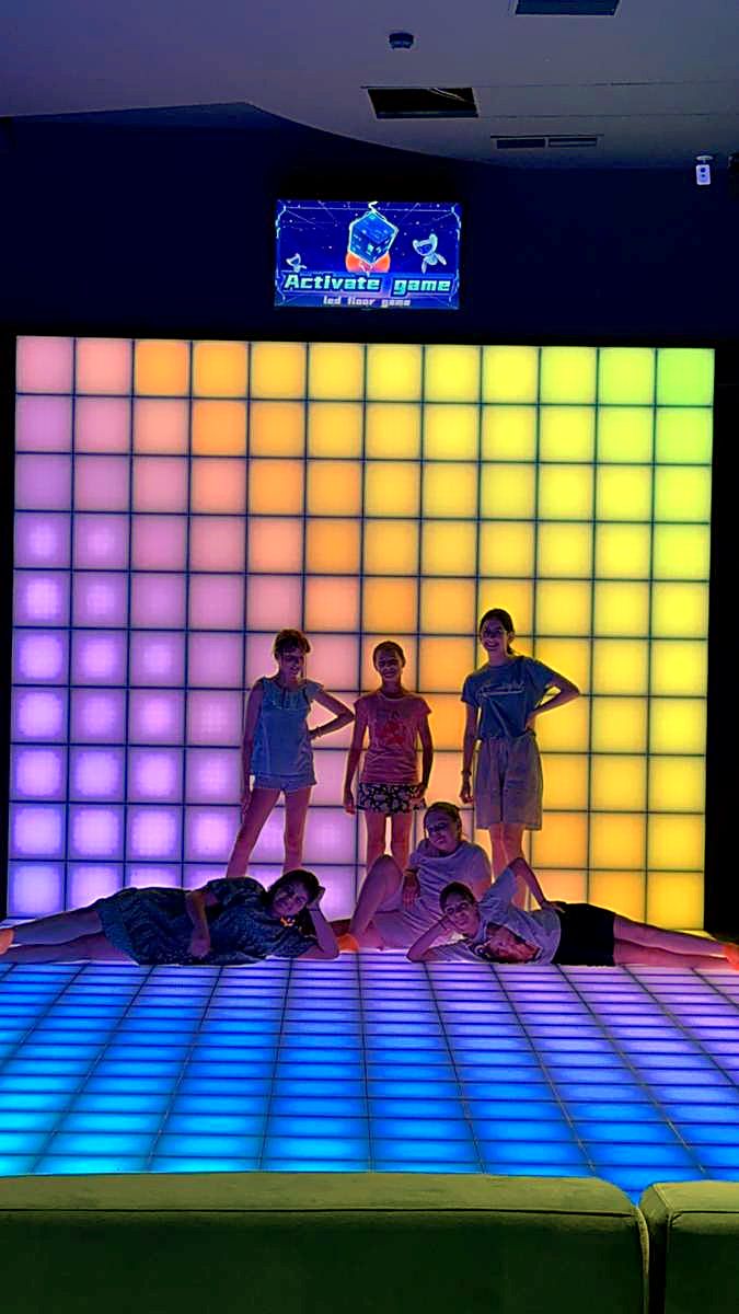 Peretele LED interactiv luminat în roz și mov, cu jucători în fața lui, la Hai Pixel din Chișinău