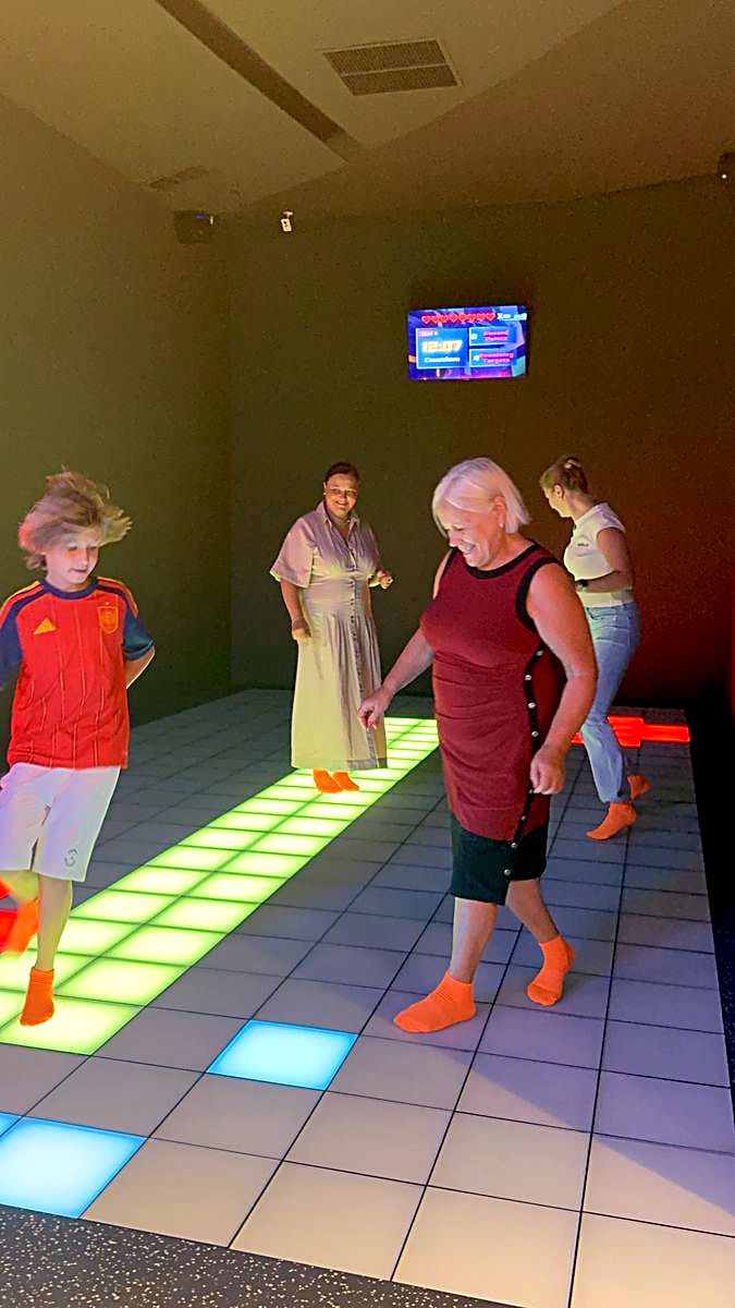 Grup de adulți de vârste diferite jucând împreună pe podeaua LED verde și albă la Hai Pixel, Chișinău